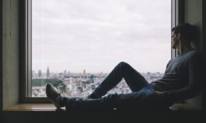 窓の外を一人で見つめる男性——後悔と決断
